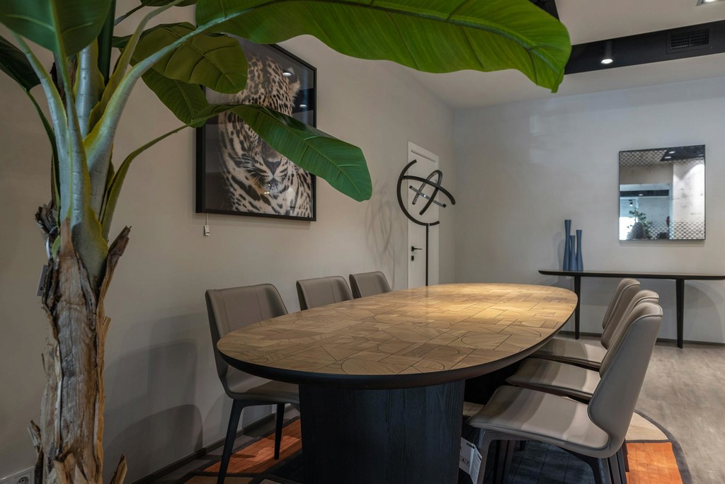 Modern dining room with a patterned wooden table, leather chairs, and a large plant
