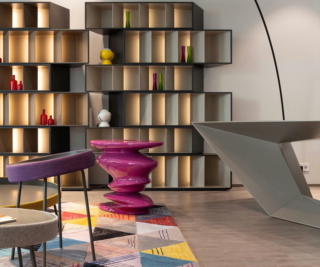 Modern shelves, purple sculptural table, and geometric desk