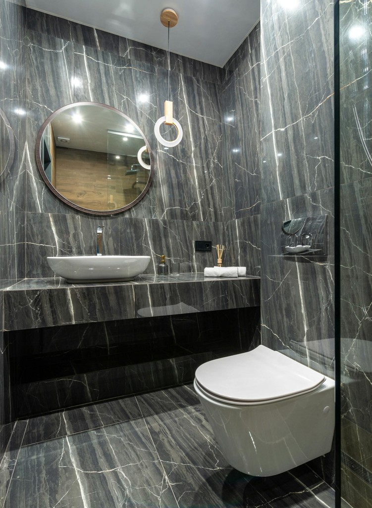 Grey marble bathroom with round mirror and floating sink